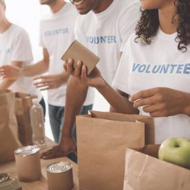 cropped shot of young volunteers group packing food and drinks for charity